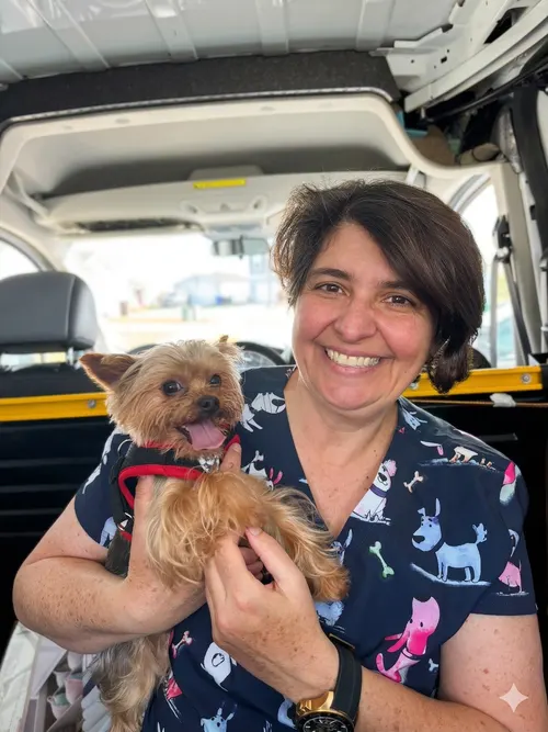 Pet Tooth Fairy professional holding a happy small dog in the mobile dental care van